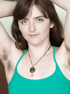 Snow Is In Her Green Top And Denim Shorts, While Lounging On Her Brown Sofa