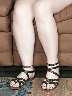 Snow Is In Her Green Top And Denim Shorts, While Lounging On Her Brown Sofa